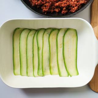Layer the zucchinis at the bottom of a dish. Make sure that the edge of zucchinis is placed on top of each other.