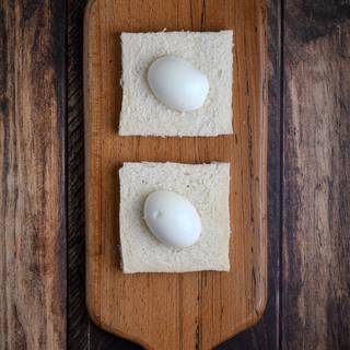 Cut out the edges of two pieces of bread. Cut the egg in half and place it in the middle of the bread.