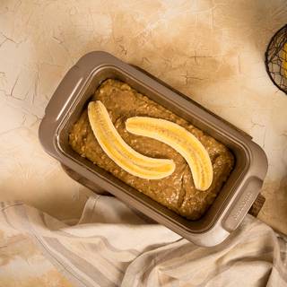 Pour the dough inside the tin. Cut a banana in half and drip some fresh lemon juice on it and place it on the dough. Put the tin inside the oven for about 50 minutes.