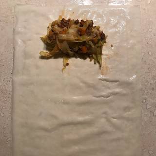 Put an egg roll wrapper on your working surface then place about 1/4 cup of the beef and vegetable mixture on the top of the egg roll wrapper.