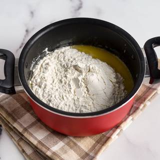 Take the pan away from the heat and add the flour to it. Stir and mix them with a wooden spoon.