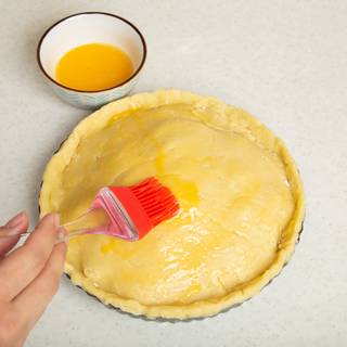 Roll out the second batch of your dough and cover your pie with it. Press the edges so they stick together and cut the excess dough. Use a soft brush to cover your pie with one beaten egg.