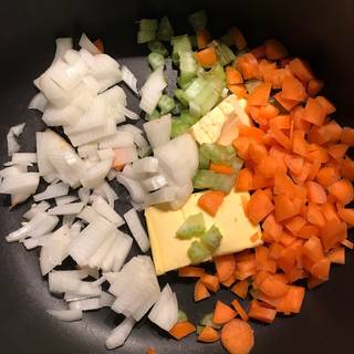 Place the butter in a pot over medium heat then add the finely chopped onions, celery and carrots.
