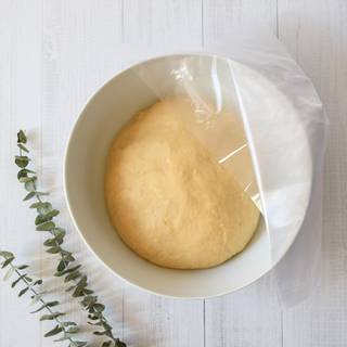 For kneading the dough you should sprinkle some flour on an even surface. Scrap out the dough onto the surface. the dough is probably a little sticky so you have to knead it until it doesn't stick to your hands. Take the dough and beat it to the work surface, you should do this about 50 to 100 times. The more you beat your dough, the better your dough will become. Grease a big bowl and put the dough inside it. Cover it with cellophane and let it rest for about one hour in a warm place. 