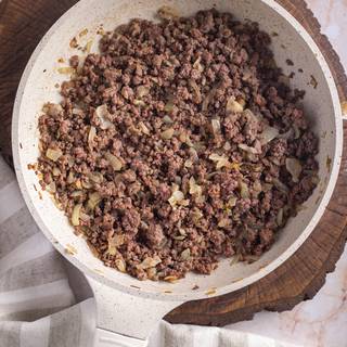 Fry the chopped onion until it becomes golden. Add ground beef and fry it as well. When the beef changed color season it with salt and pepper.