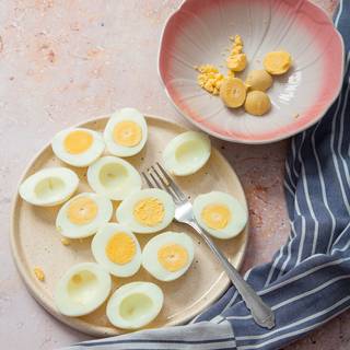 Slice the eggs in half lengthwise and set them on a platter or egg plate. Scoop the yolks into a medium bowl.