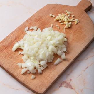 At first, chop the garlic and onions and fry them in a greased pan.