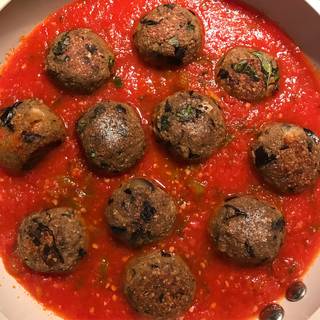Pour the homemade tomato sauce in a skillet and place the cooked eggplant meatballs into the sauce.