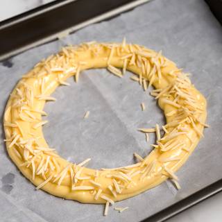 pipe a circle on the parchment paper. pipe another circle outside it. On top of the circle pipe another layer of your dough. Give it an egg wash and sprinkle some chopped almonds on top of it. Let it bake in the preheated oven at 180C for 35 to 40 minutes, then turn it off, open the door and let it stay there for 15 more minutes. 