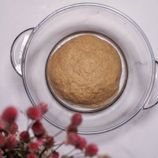 Mix the ingredients with a wooden spoon to make your sticky dough. Now sprinkle some flour on a surface and knead the dough for about 5 minutes. Add more flour when you see the dough is sticking to your hand. Grease a clean dish and put your dough inside it and cover it with cellophane or some cloth.