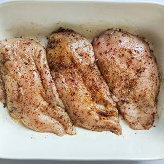Flipping chicken breast over in order to dip to the spices thoroughly.
