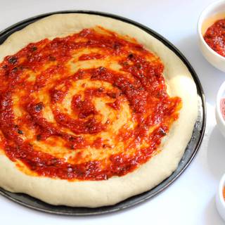 Rub the tomato sauce on the dough and add as much red pepper as you like.