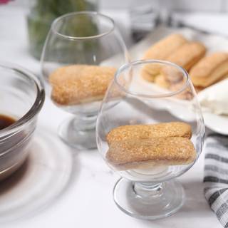 Rolling ladyfingers in coffee and put them on plate, but please pay attention. Don't let ladyfingers be submerged for a long time in the coffee because they will become soggy and as a result, the whole tiramisu becomes wet.