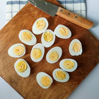 Halve the eggs with a sharp knife. Then, dispart the yolks with a spoon without harming the albumen.