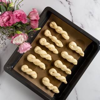 After one hour cut your dough to 16 even pieces and roll each one with your hands to ropes, fold them in half twist them like the picture, and stick the end with your hands. Cover and let them rest again for 15 more minutes. 