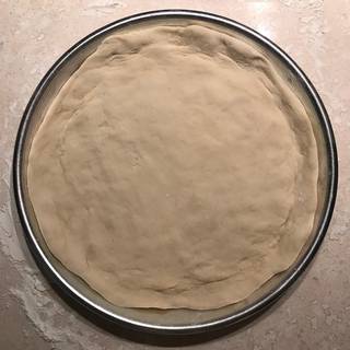 Press the pizza dough into a greased pizza pan.
