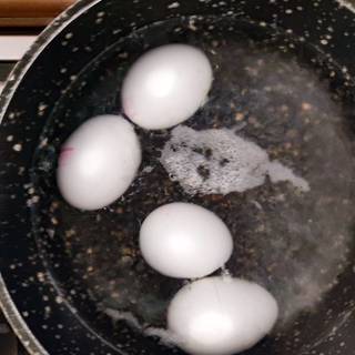 Fill a pot with cool water and add the eggs. Bring the water to a boil, cover, and turn off the heat after 10 minutes.