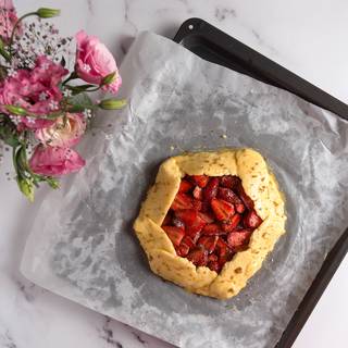 With the help of parchment paper, fold the edges of the dough to the center of the filling. And brush eggs on the edges of the dough. Besides, sprinkle sugar on the surface of it.