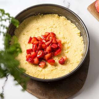 Use 2/3 of the dough to cover the bottom of the pan and make it smooth and even by pressing it with a spoon or your hands. Place the strawberries on top of the dough.