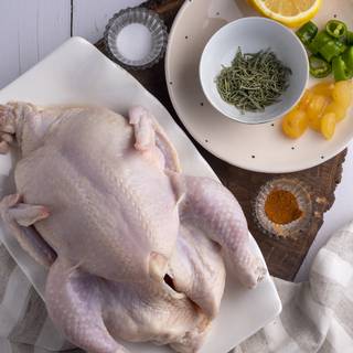 Wash the chicken with water and dry it with a piece of cloth. Sprinkle some salt and pepper inside and outside of your chicken. Put 5 garlic cloves, half a green chili, half of the lemon, and one tablespoon of fresh or dried rosemary inside your chicken.