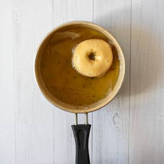 Fill the pan with oil so that your doughnuts would flout in it. Put the pan on the heat to become hot. Put the doughnuts inside the pan then you can remove the parchment paper. Flip the doughnuts so both sides are fried perfectly. At last, you can take them outside the pan and put them on a towel to absorb the extra oil.