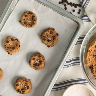 Scoop the dough ‌ or roll it by hand.‌ put it on greaseproof paper in the tray and press it with a spoon until it is flat.