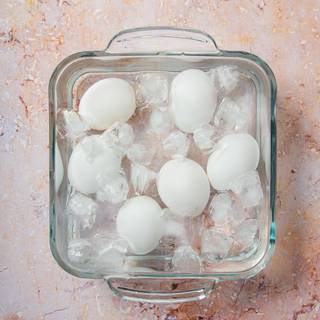  Transfer the eggs from the hot water and into a bowl of ice-cold water and let cool completely. When the eggs are cold, peel under the water in the bowl or under running water.