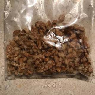 Fill a plastic bag with walnuts then gently beat them with a rolling pin until the walnuts are crashed into smaller pieces.