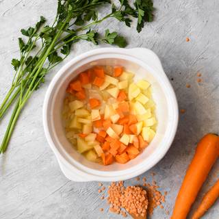 Chop the onion and fry in an oily pot until it becomes golden. Peel carrots and potatoes and cut them into cubes and fry them with the onions. 