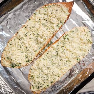 Grate the parmesan cheese and sprinkle it on the bread. Put the bread inside the oven for about 10 to 15 minutes at 170C.