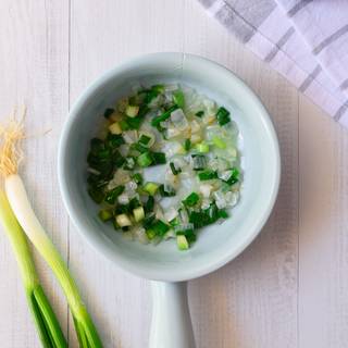 After making our crepes we need to prepare the filling. chop the onions and fry them in a pan. Then add the chopped spring onions and grated garlic to the onions and fry them.