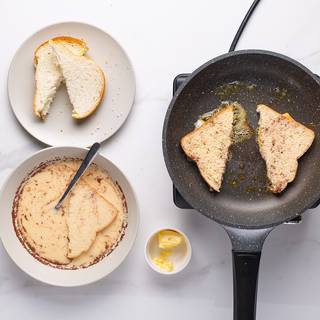 Place each slice of bread into the milk-egg mixture, allowing the bread to soak in some of it. Melt some butter in a large skillet over medium-high heat. 