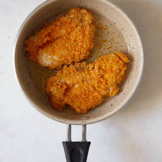 Fry the chicken pieces in a deep pan full of hot oil until they are golden.