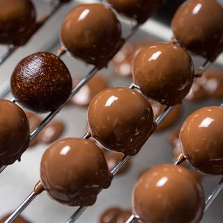 Melt 100 grams of chocolate over a bain-marie or in the microwave. Place the truffles on a grate and coat them with melted chocolate.
