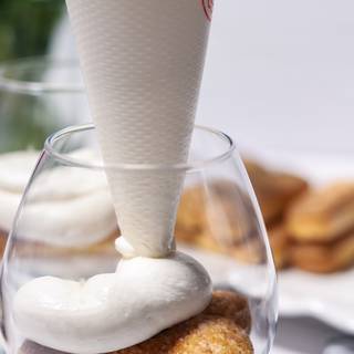 Pour cream into the funnel. Now, pour one layer of creamy ingredients with the funnel on ladyfingers.