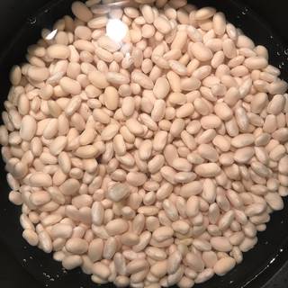 Drain and rinse the beans, put them in a pot over high heat and pour in about 2 to 3 glasses of water too. bring it to a boil then reduce the heat to low and cook.