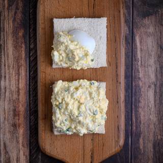 Cover the pieces of bread equally with egg salad. Put them on top of each other. and cut them in half with a sharp knife.