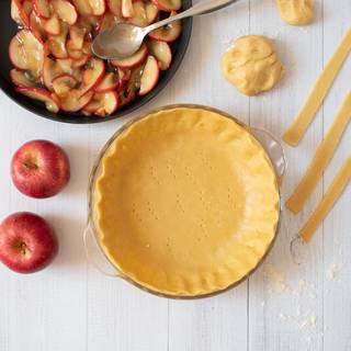 Roll out the dough with a rolling pin and make it about 3 inches bigger than your baking pan. Put the dough inside the pan and cut the extra with a knife. fill the pie crust with the apples.