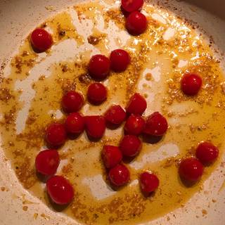 Now remove the cooked chicken from the skillet and set aside add minced garlic, cherry tomatoes and salt , saute for about 2 minutes until the tomatoes are tender.