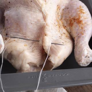 After filling the chicken's cavity you can sew it with thread and a needle to prevent the stuff from coming out of it. Truss the chicken with cooking twine. 