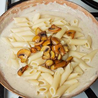 Add cooked pasta and mushrooms to the sauce. Stir it well