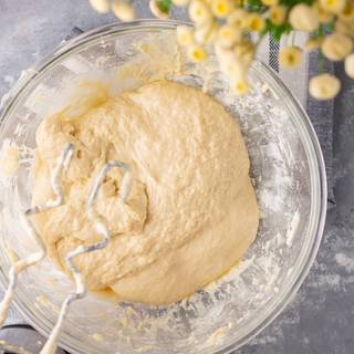 Whisk the dough with a mixer on medium speed until it is formed. Grease a big bowl and put the dough inside. Cover the bowl and let it rest in a warm place for one hour until it becomes double in size.