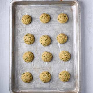 Grease the oven tray. Use a spoon or a scoop to shape the falafel dough and place it on the tray. You can also spray some oil on your falafels if you want to. Cover the tray with foil and put it inside the oven.