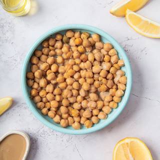 The main ingredient for the hummus is chickpeas. You can cook them yourself or buy them canned. If you want to cook them yourself, soak them in water overnight and change the water a couple of times. You can cook the chickpeas the next day in the water on low heat until they become soft.