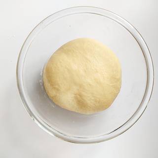 Spread some flour in a bowl and put the dough inside it. Cover the bowl with plastic wrap and set it in a warm and dark place to rise for 1 hour and a half. After that, the dough should have nearly doubled in size. 