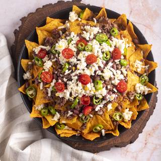 Cover the last layer of tortillas with beef and beans. Add cheese, green pepper, and cherry tomatoes to it.