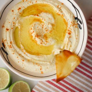 Finally, pour the hummus on a plate. Dig a little with a spoon. Pour a little olive oil and garnish with red pepper and pita bread.
