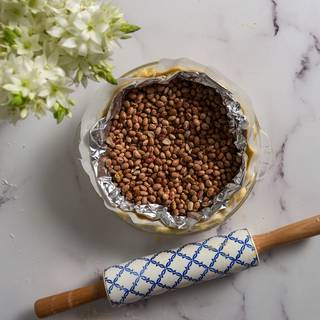 Put some foil on the parchment paper and fill it with beans. Preheat the oven at 200C and bake your crust for 15 to 20 minutes, then take it out and remove the foil and the parchment paper.