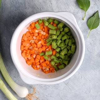 Fry the chopped onions in olive oil in a pot until they become golden. Mash the garlic and add them to the onions. Now add the carrots and chopped green beans.