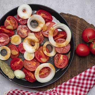 Cut the tomatoes in half, chop the onions and place them on the oven tray with the garlic, salt, pepper, olive oil, and bey laurel. Cook them in the oven at 200C for 40 minutes. 